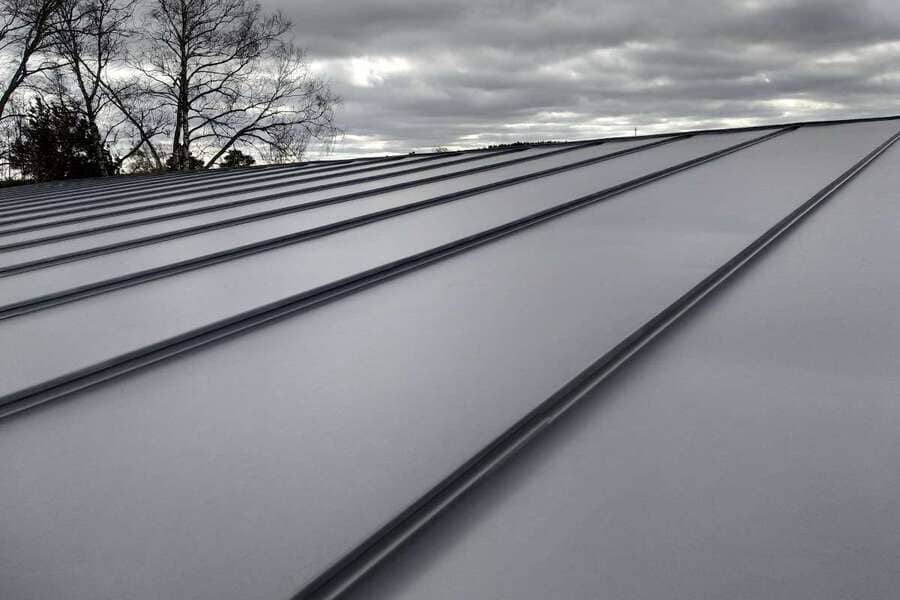 Metal roof with standing seam detail under an overcast sky.